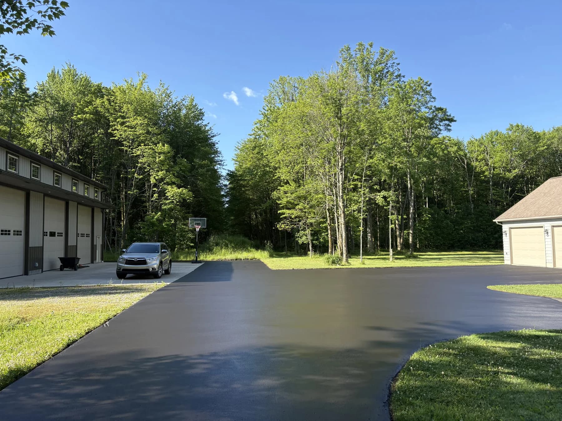 The same wide driveway freshly hand-sealed deep black, the day Tommy finished