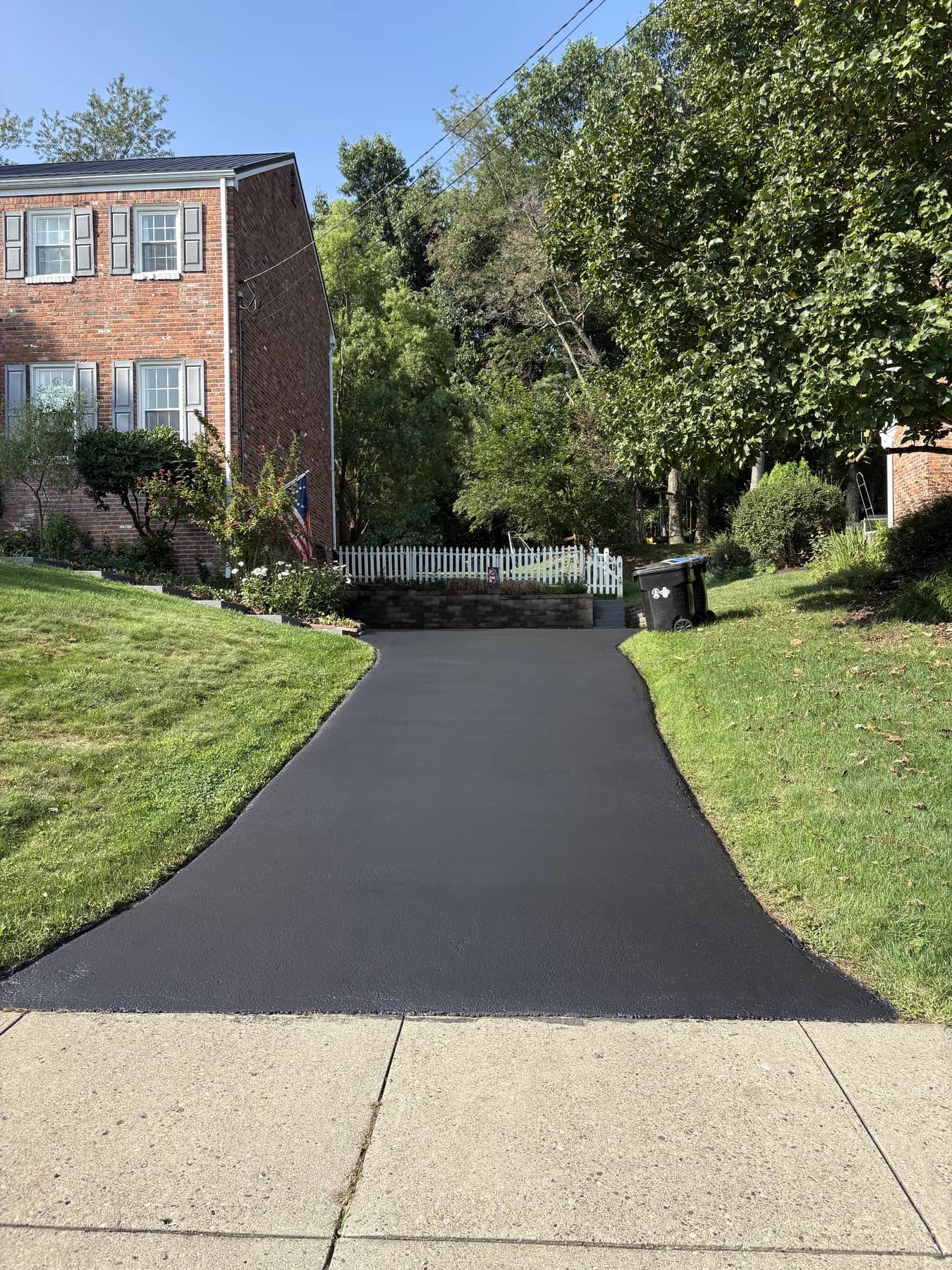 The same driveway freshly hand-sealed deep black, the day Tommy finished