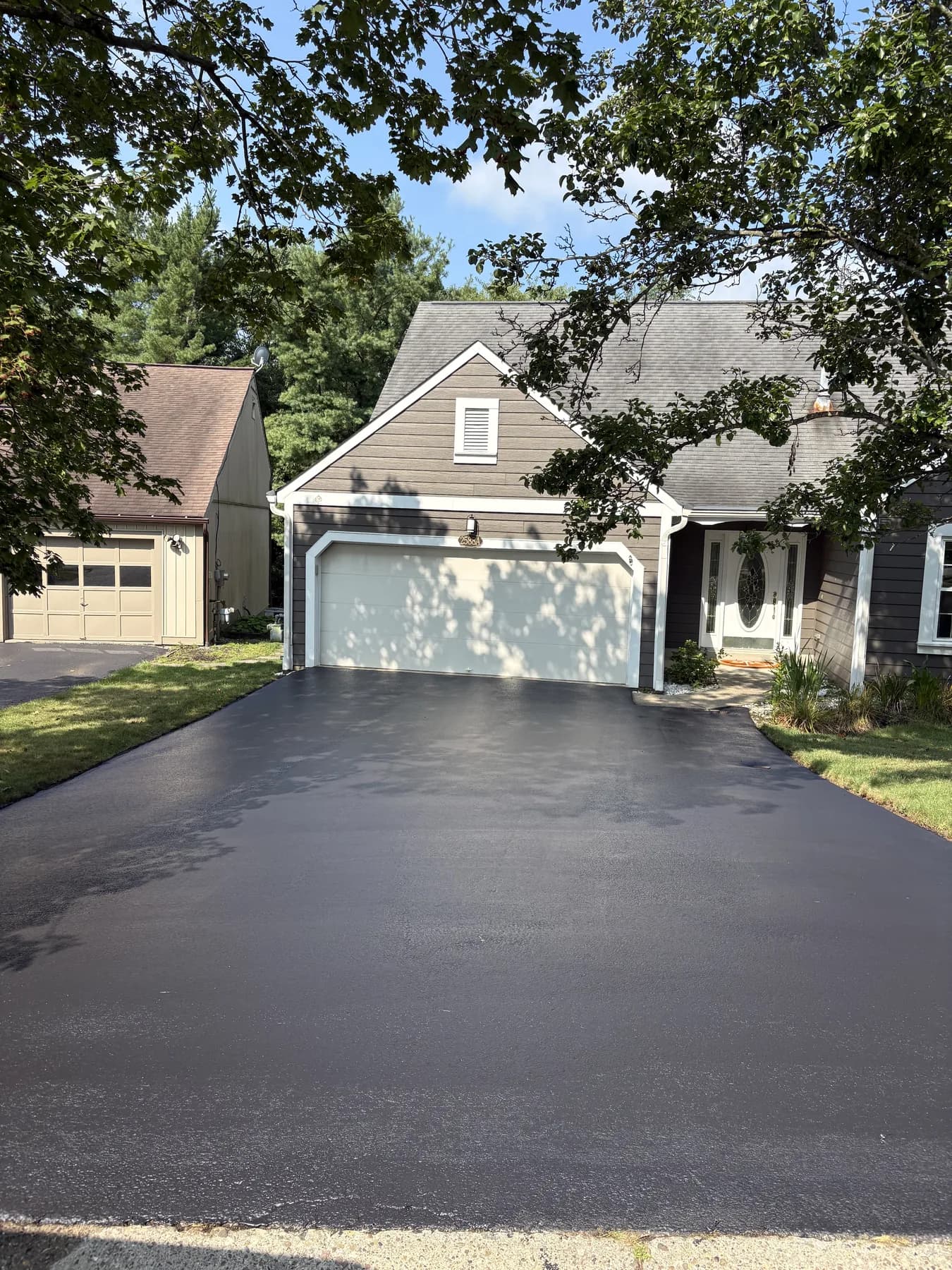 The same garage driveway freshly hand-sealed deep black