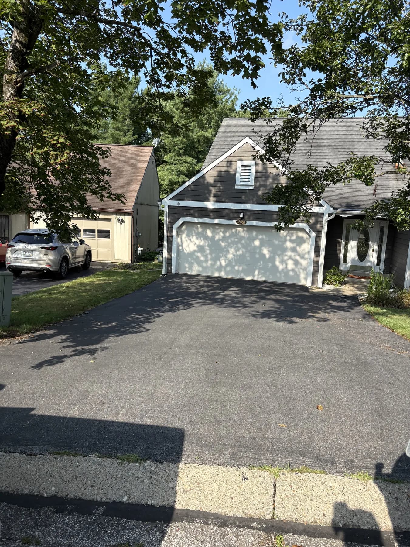 Worn, faded driveway in front of a two-car garage before sealcoating