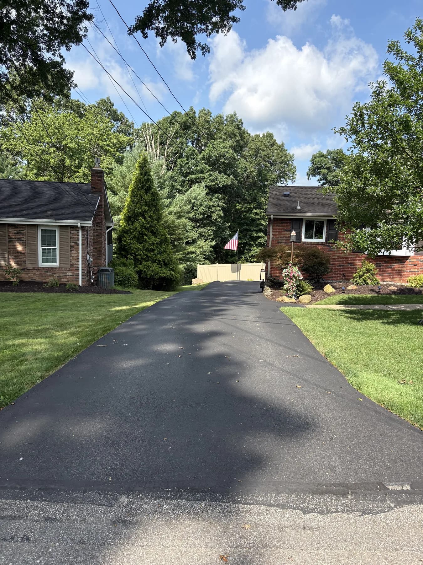 Long faded driveway between brick ranch homes before sealcoating